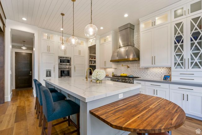 Kitchen featuring appliances with stainless steel finishes, decorative backsplash, wall chimney exhaust hood, and white cabinets | Image 26
