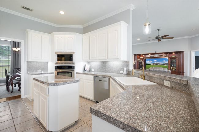 Kitchen featuring appliances with stainless steel finishes, ceiling fan, tasteful backsplash, decorative light fixtures, and crown molding | Image 17