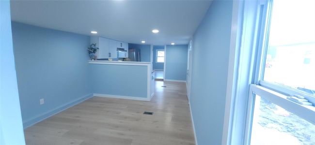 Kitchen with light wood-style floors, freestanding refrigerator, a peninsula, white cabinets, and recessed lighting | Image 11