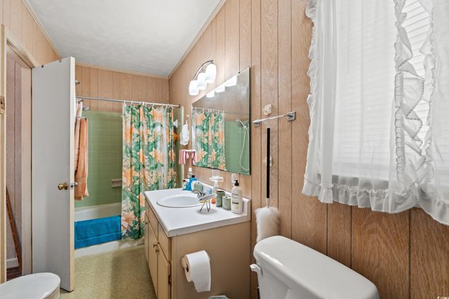 Full bath featuring vanity, wooden walls, and shower / bath combo with shower curtain | Image 9