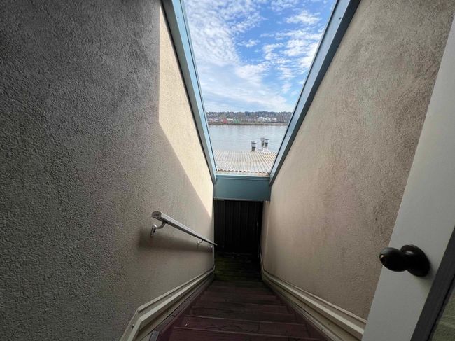 Stairs featuring a textured wall, a water view, and wood finished floors | Image 7