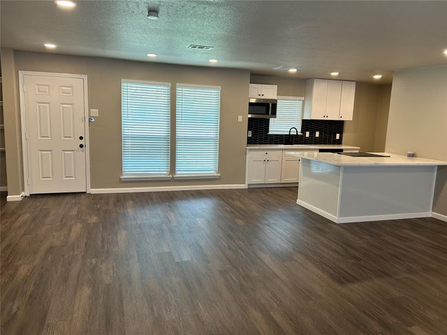 Kitchen featuring stainless steel microwave, dark wood-style flooring, white cabinets, baseboards, and recessed lighting | Image 21