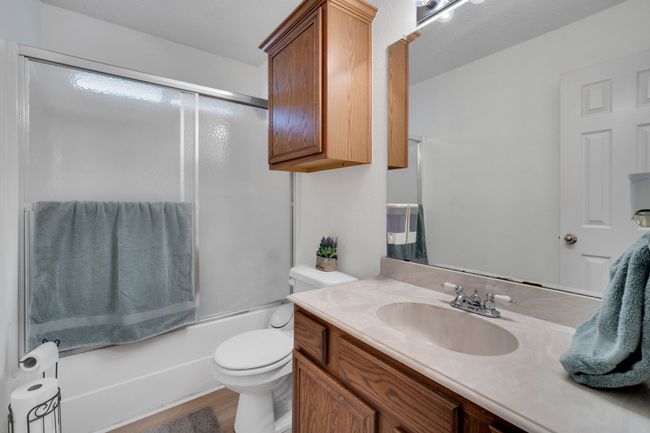 Bathroom featuring vanity, bath / shower combo with glass door, and wood finished floors | Image 23