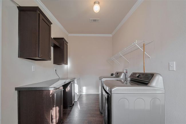 This laundry room boasts a modern washing machine and ample cabinetry for all your storage needs. | Image 19