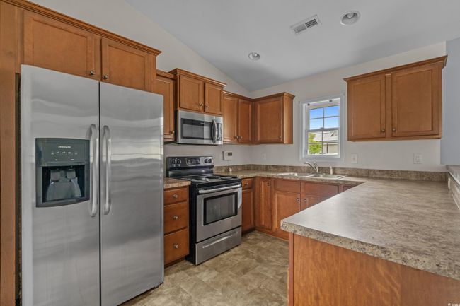 Kitchen with stainless steel appliances, a sink, brown cabinetry, lofted ceiling, and recessed lighting | Image 19