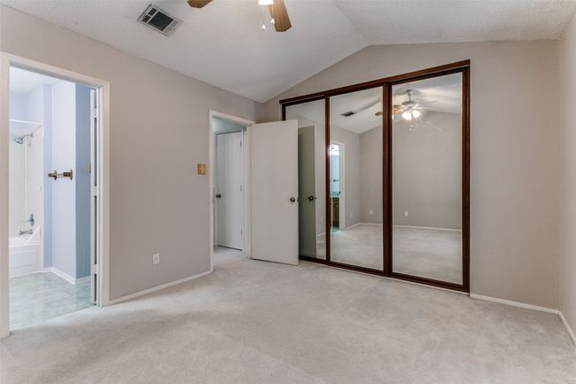 Unfurnished bedroom featuring lofted ceiling, carpet floors, a closet, ensuite bathroom, and ceiling fan | Image 17