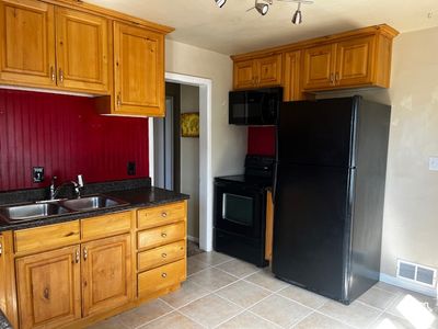 Kitchen with black appliances, sink, and light tile patterned floors | Image 3