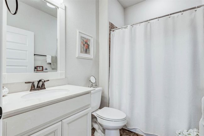 The secondary full bathroom features a white vanity with a framed mirror, bronze fixtures, and a tub/shower combination for added convenience. | Image 21