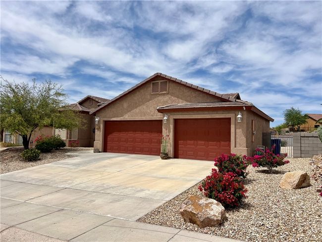 Ranch-style house with stucco siding, an attached garage, fence, and driveway | Image 4