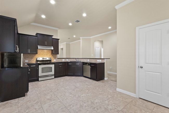 Kitchen featuring appliances with stainless steel finishes, arched walkways, under cabinet range hood, backsplash, and crown molding | Image 10