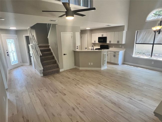 Kitchen featuring black microwave, white cabinetry, open floor plan, and light wood finished floors | Image 10