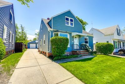 Bungalow featuring an outdoor structure, a garage, and a front lawn | Image 2