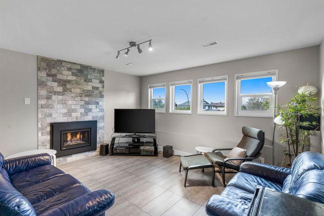 Tiled living room with a large fireplace and visible vents | Image 21