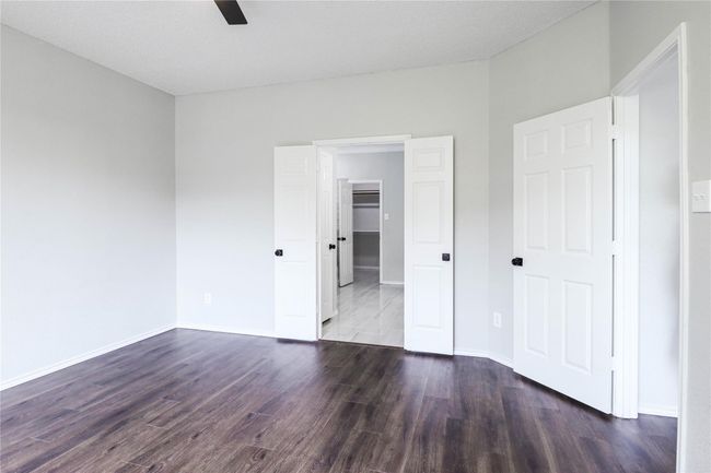 Unfurnished bedroom with dark wood-style floors, baseboards, and a ceiling fan | Image 11