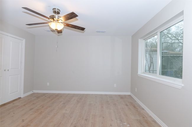 Empty room featuring light wood-style flooring, baseboards, visible vents, and ceiling fan | Image 9