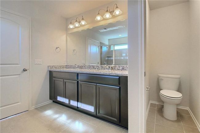Bathroom with double vanity, tile patterned floors, baseboards, and toilet | Image 29