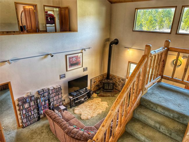 Carpeted living room with a wood stove and stairway | Image 23