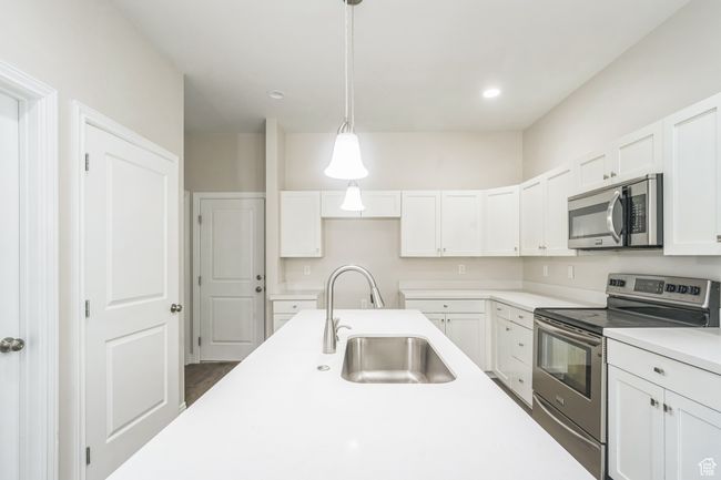 Kitchen with stainless steel appliances, white cabinetry, light countertops, pendant lighting, and recessed lighting | Image 10