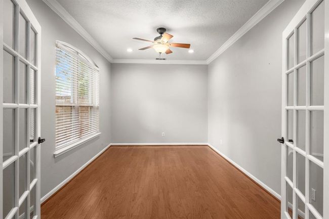 Home office is ideally situated at the front of the house for added privacy, with sun-filled windows that flood the space with natural light and offer serene views of the front lawn. Additional features include recessed lighting, a ceiling fan for comfort, and elegant French doors that enhance both style and function. | Image 5