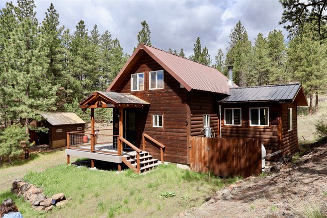 Rear view of house featuring a wooden deck, metal roof, and faux log siding | Image 8