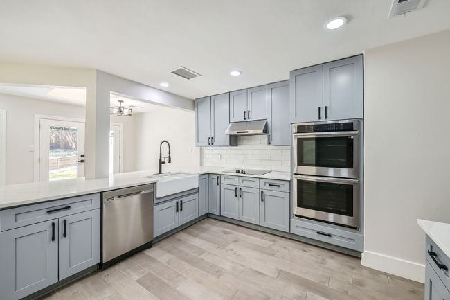 Kitchen with gray cabinetry, a sink, stainless steel appliances, and visible vents | Image 10