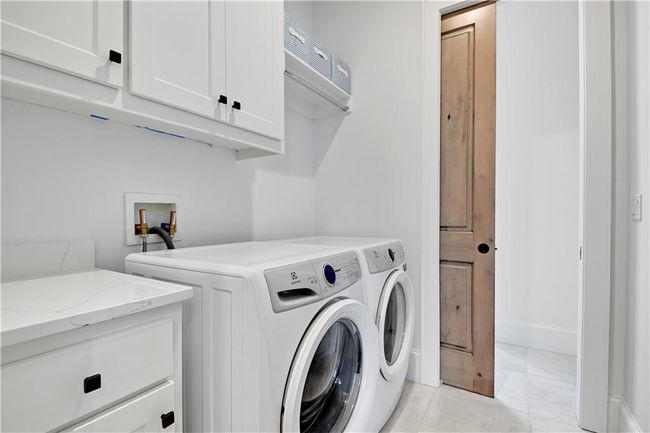 Washroom with independent washer and dryer, light tile patterned floors, and cabinet space | Image 38