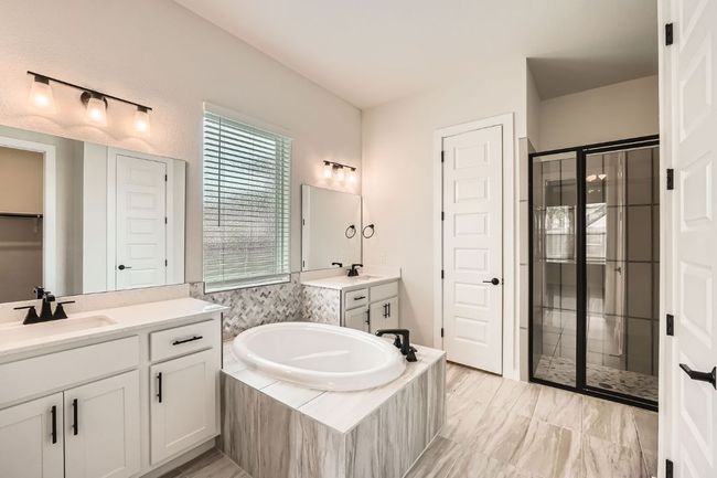 Full bath featuring a stall shower, a garden tub, a closet, and two vanities | Image 17