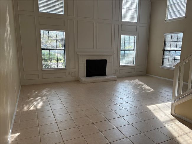 Unfurnished living room featuring a high ceiling, a decorative wall, light tile patterned flooring, and a wealth of natural light | Image 4