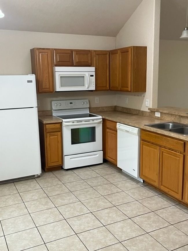 Kitchen with white range with electric cooktop, sink, dishwashing machine, light tile patterned floors, and refrigerator | Image 5