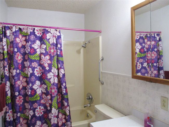 Full bath with a textured ceiling, toilet, vanity, tile walls, and shower / bath combination with curtain | Image 14