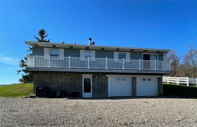 Back of property with a garage, central air condition unit, and a balcony | Image 2