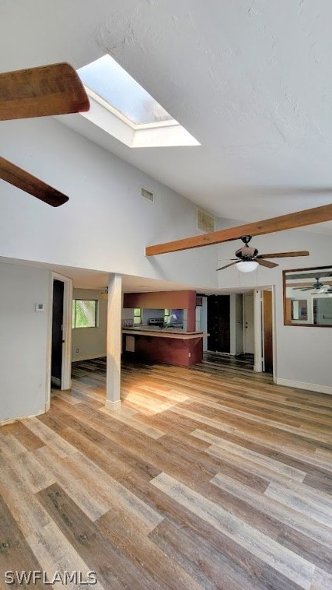 Living room with beamed ceiling, hardwood / wood-style flooring, high vaulted ceiling, ceiling fan, and a skylight | Image 6