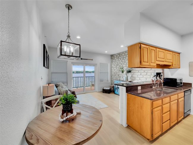 Kitchen with a sink, light wood-style floors, black microwave, dishwashing machine, and open floor plan | Image 6
