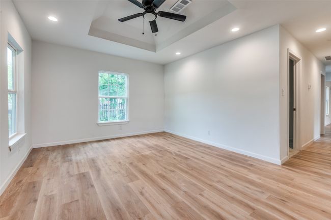 Unfurnished room with a tray ceiling, light wood-style flooring, visible vents, and a ceiling fan | Image 6