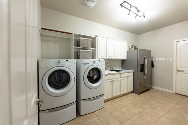 Laundry area with cabinet space, light tile patterned floors, and washer and clothes dryer | Image 19