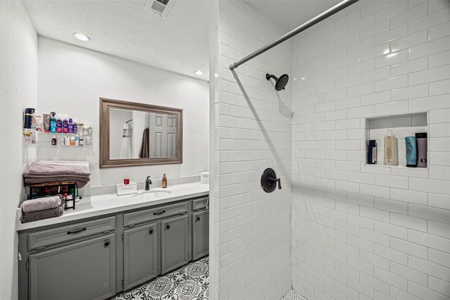 This bathroom features a modern design with a spacious walk-in shower, white subway tiles, and a built-in shelf. | Image 21