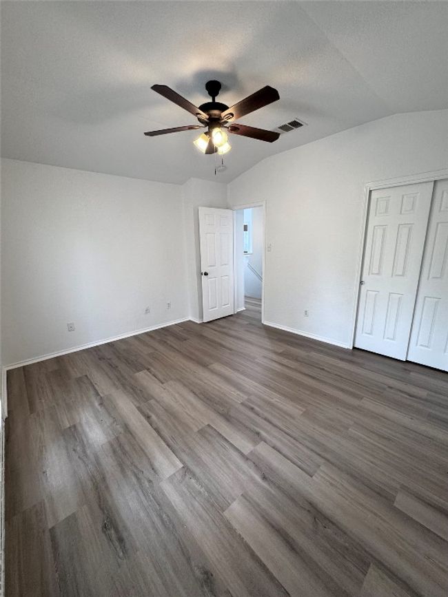 Unfurnished bedroom with vaulted ceiling, dark wood-style floors, a ceiling fan, and a closet | Image 28