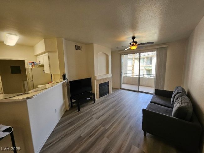 Living area with a ceiling fan, a fireplace, baseboards, dark wood-type flooring, and visible vents | Image 30