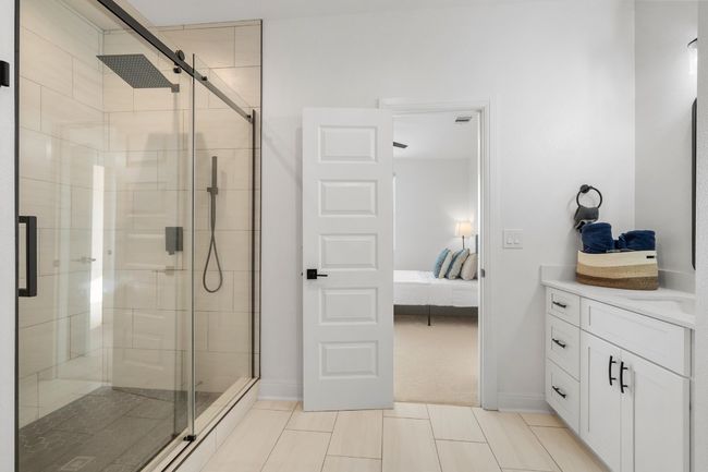 A generously sized guest suite on the second level features a luxurious full bath with an oversized walk-in shower, quartz countertops, premium finishes, and a spacious walk-in closet—blending sophistication and comfort effortlessly. | Image 25