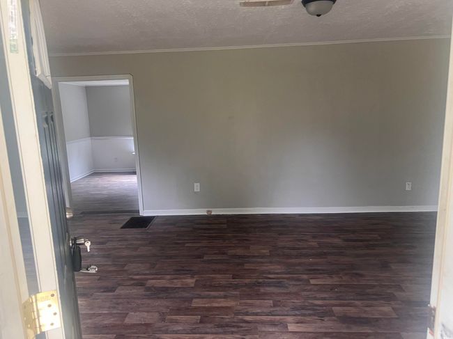 Spare room featuring dark wood finished floors, a textured ceiling, baseboards, and crown molding | Image 5