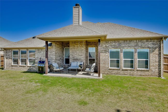 Rear view of property featuring a chimney, a patio, a yard, and brick siding | Image 30