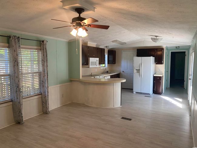 Kitchen with white appliances, dark brown cabinetry, light countertops, a ceiling fan, and a textured ceiling | Image 11