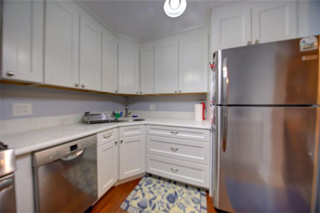 Kitchen with light countertops, appliances with stainless steel finishes, a sink, and white cabinetry | Image 8