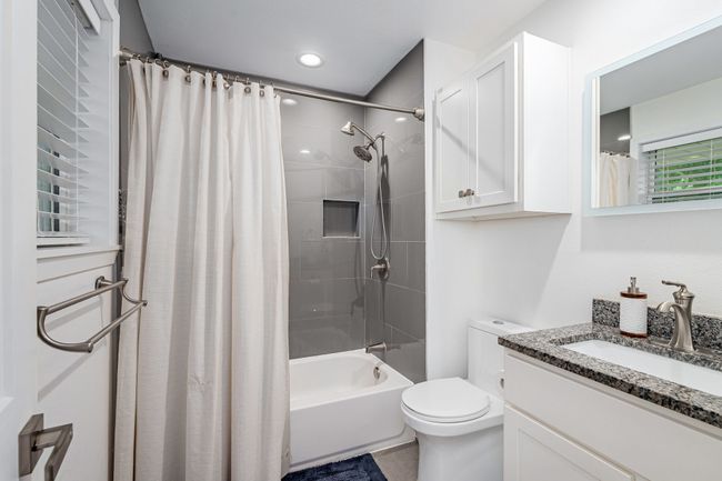The primary bathroom has a granite vanity top, cabinet above the toilet area, updated fixtures & stylish tile. | Image 19