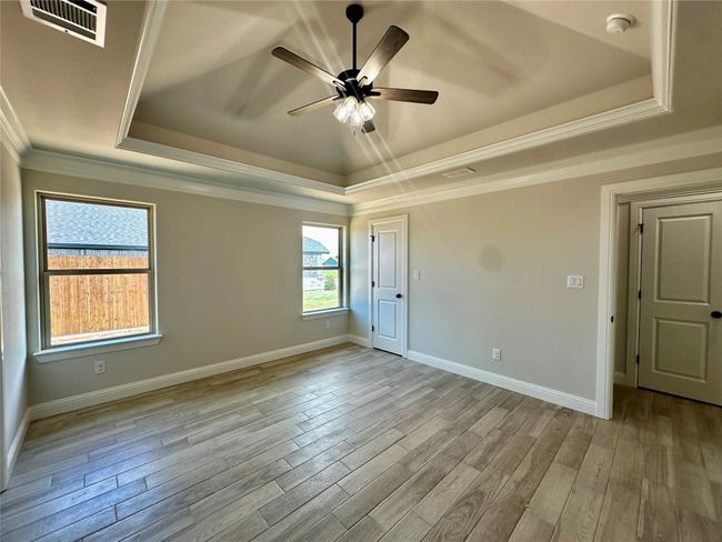 Spare room featuring a tray ceiling, a smoke detector, a ceiling fan, baseboards, and crown molding | Image 12
