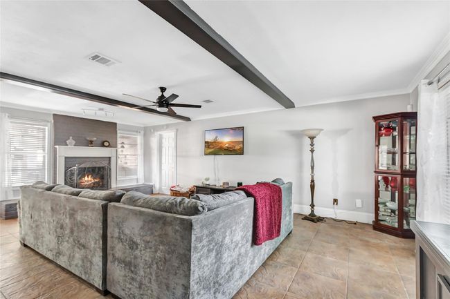 Large living space with decorative beams and a wood burning fireplace. | Image 11