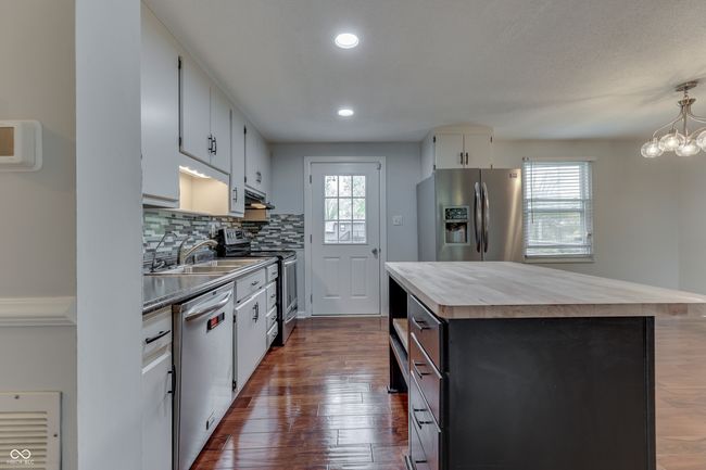 kitchen with butcher block countertops, a sink, appliances with stainless steel finishes, and a healthy amount of sunlight | Image 13