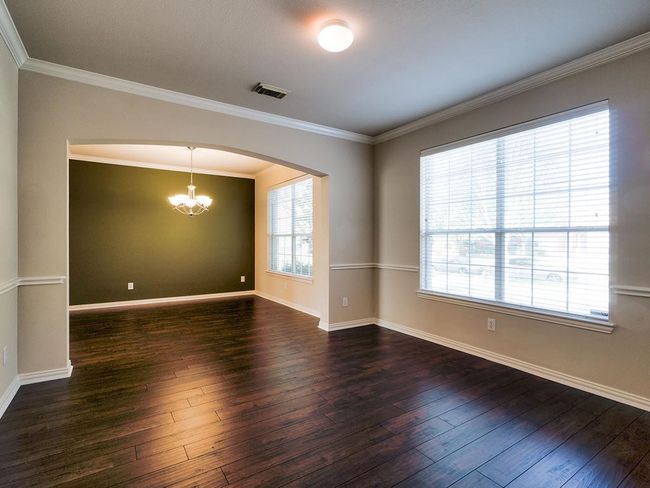 Unfurnished room with a chandelier, arched walkways, hardwood / wood-style floors, baseboards, and crown molding | Image 8