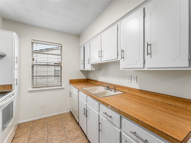 Kitchen featuring sink, light tile patterned floors, white cabinets, and white appliances | Image 12