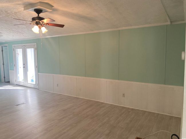 Unfurnished room featuring a textured ceiling, ceiling fan, wood finished floors, a decorative wall, and ornamental molding | Image 10
